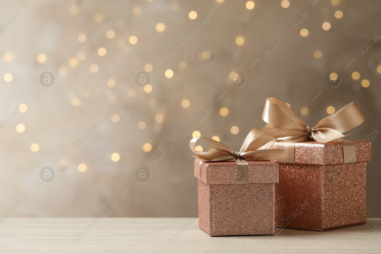 Photo of Beautiful gift boxes on light table against blurred festive lights, space for text