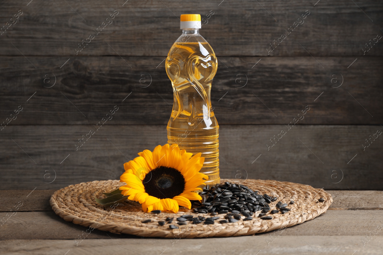 Photo of Sunflower cooking oil, seeds and yellow flower on wooden table