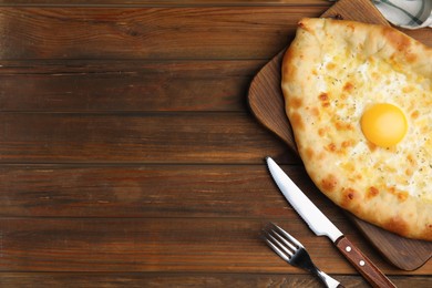 Photo of Fresh homemade khachapuri with cheese and egg served on wooden table, flat lay. Space for text