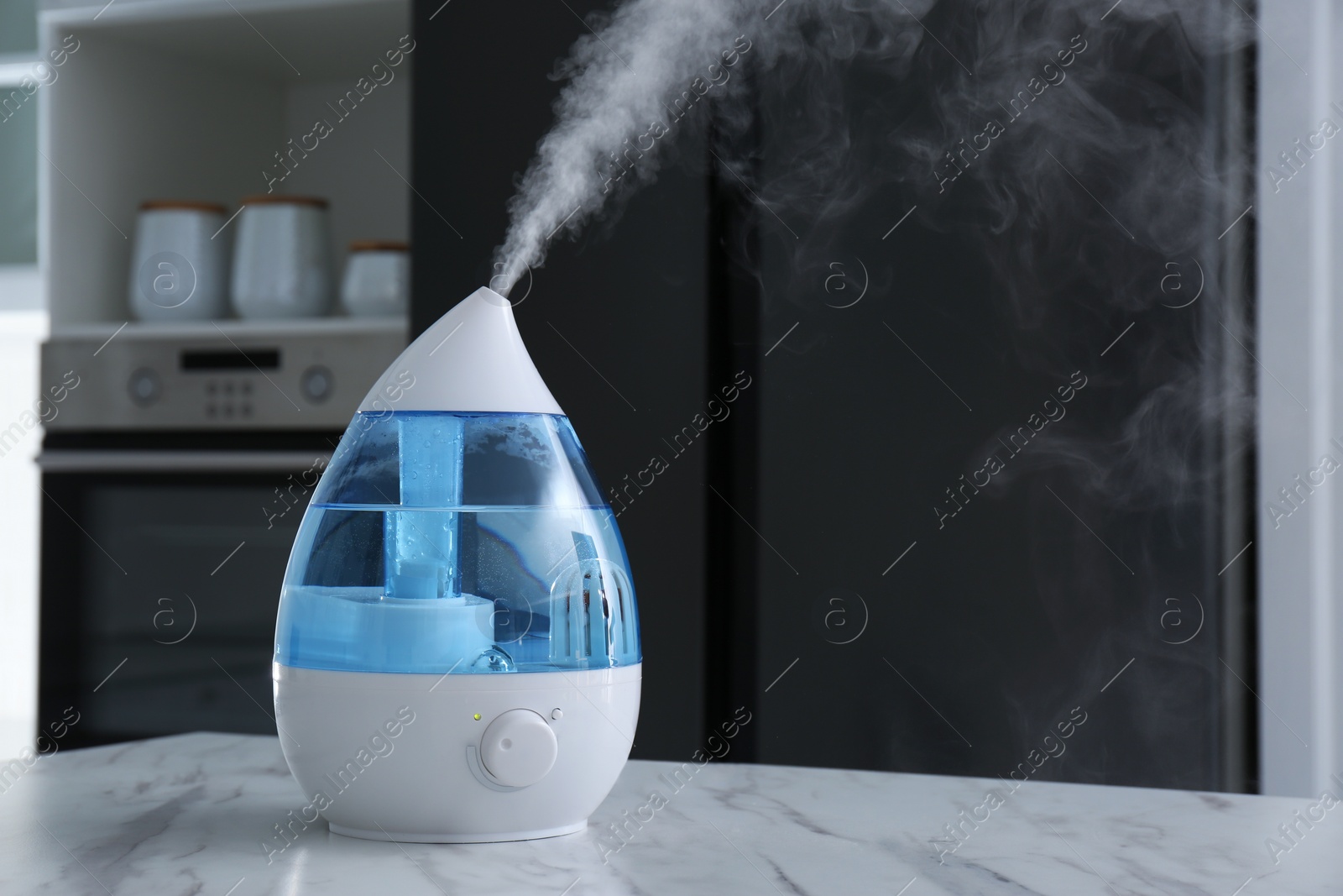 Photo of Modern air humidifier on marble table in kitchen. Space for text