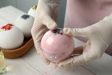 Woman in gloves making bath bomb at white table , closeup