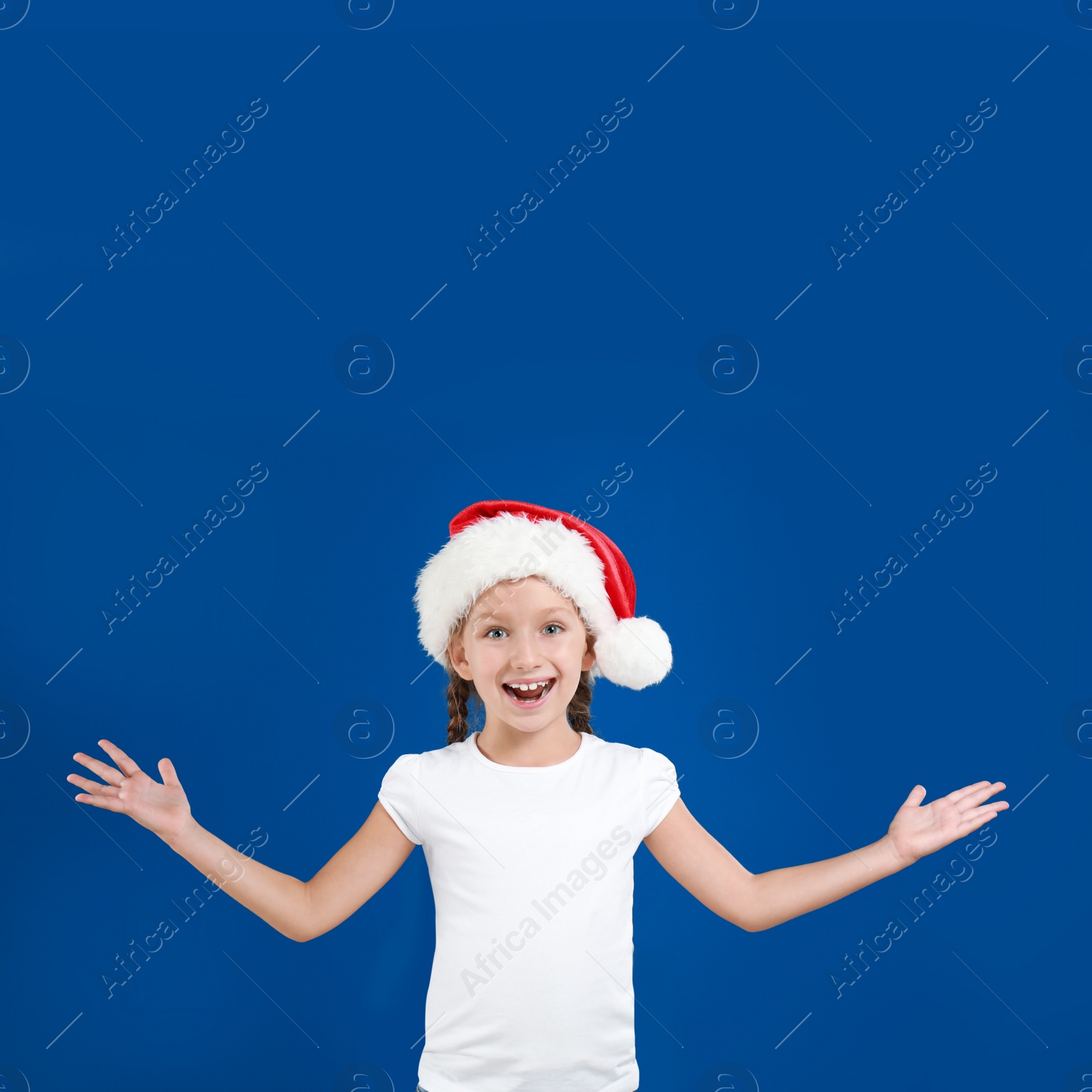 Image of Happy little child in Santa hat on blue background. Christmas celebration