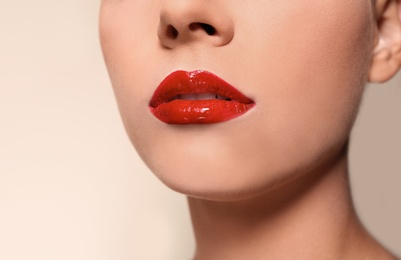Photo of Beautiful young woman with red glossy lips on color background, closeup
