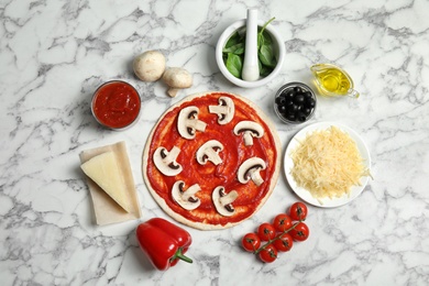 Flat lay composition with pizza crust and ingredients on marble table