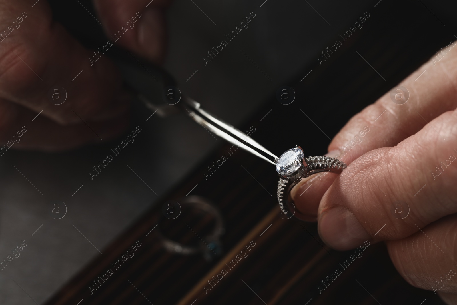 Photo of Professional jeweler working with ring at table, closeup