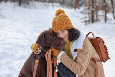 Woman with adorable Labrador Retriever dog in snowy park