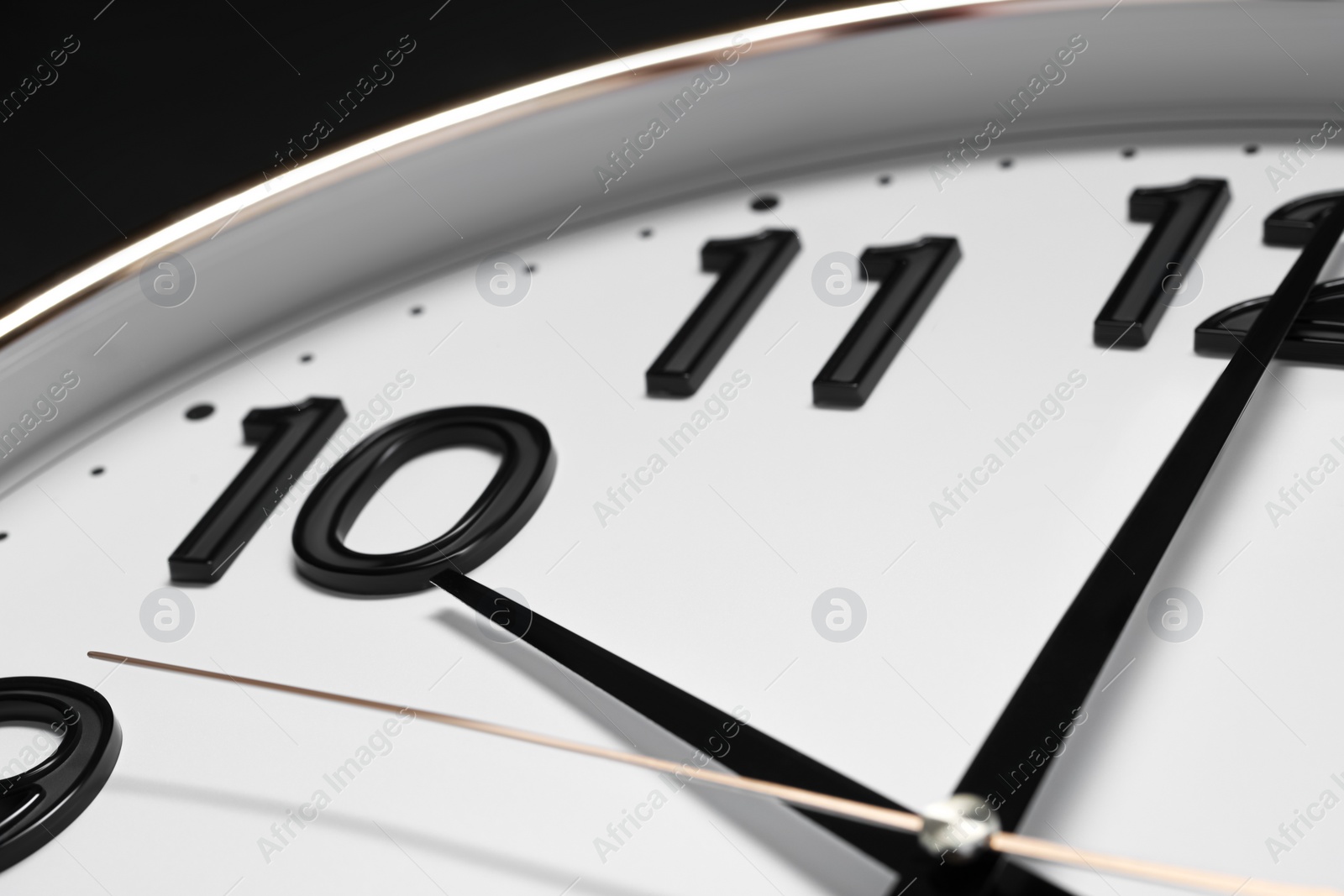 Photo of Stylish round clock on black background, closeup. Interior element