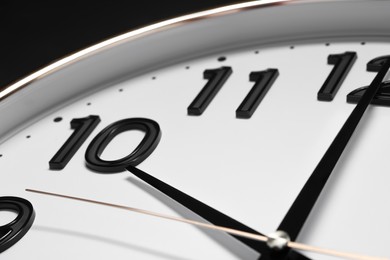 Stylish round clock on black background, closeup. Interior element