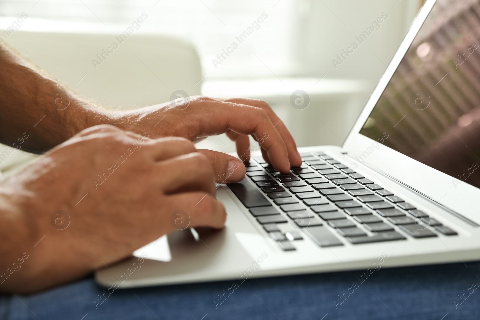 Photo of Man using laptop for search indoors, closeup