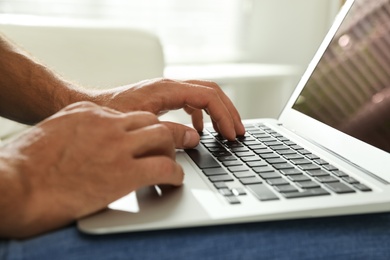 Photo of Man using laptop for search indoors, closeup