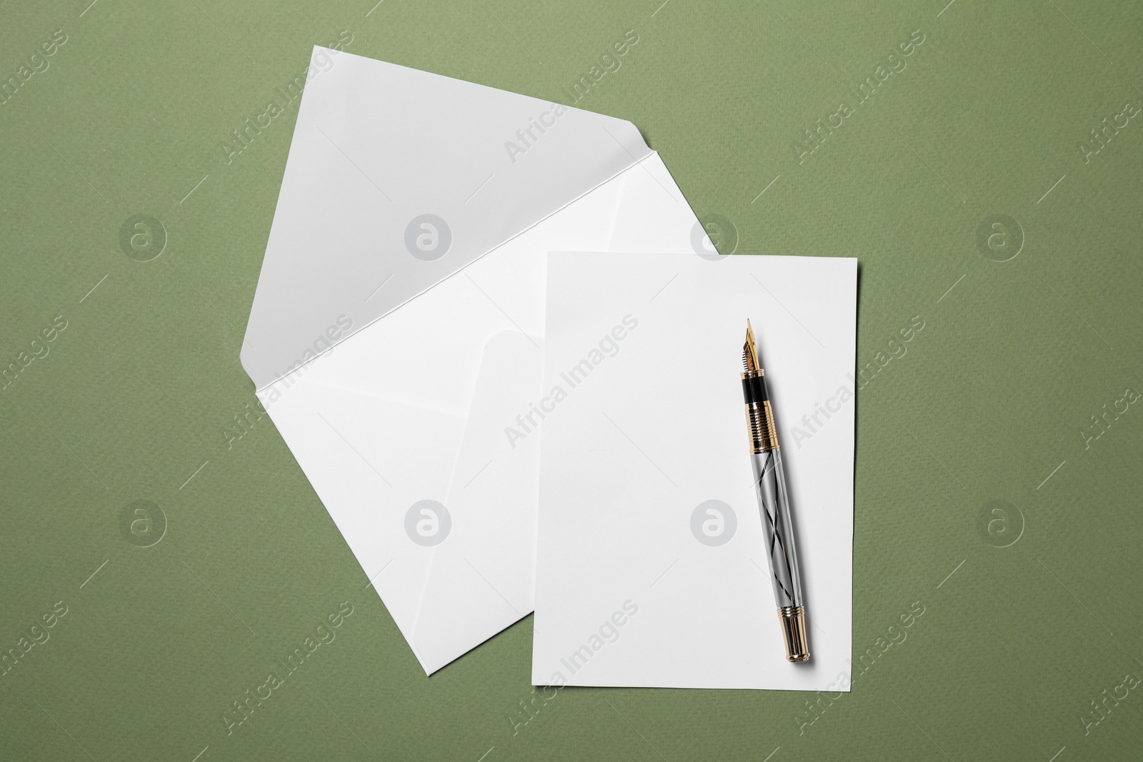 Photo of Blank sheet of paper, letter envelope and pen on green background, top view