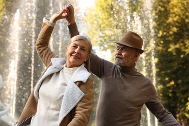 Photo of Affectionate senior couple dancing together near fountain outdoors. Romantic date