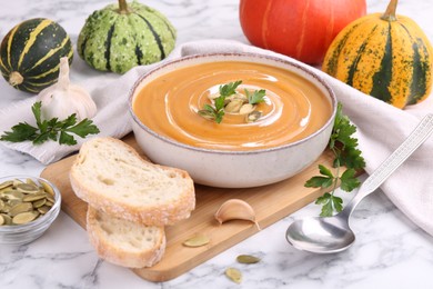 Photo of Delicious pumpkin soup served on white marble table