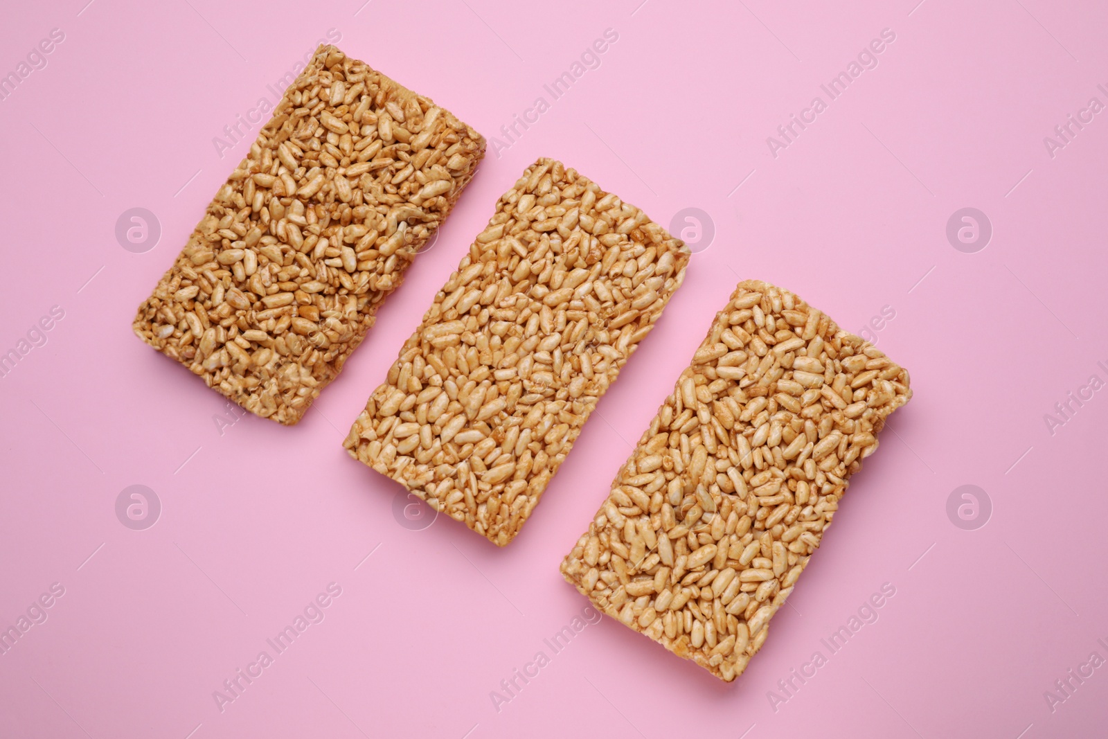 Photo of Puffed rice bars (kozinaki) on pink background, flat lay