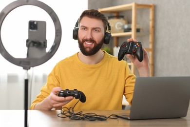 Photo of Smiling technology blogger recording video review about game controllers at home