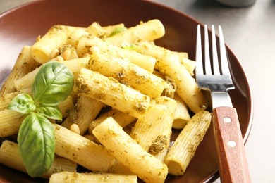 Photo of Plate of delicious basil pesto pasta on table, closeup