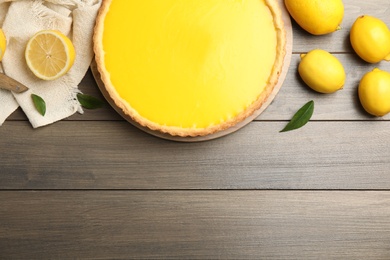 Photo of Delicious homemade lemon pie and fruits on wooden table, flat lay. Space for text