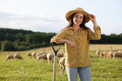 Portrait of smiling woman with shovel on pasture at farm. Space for text