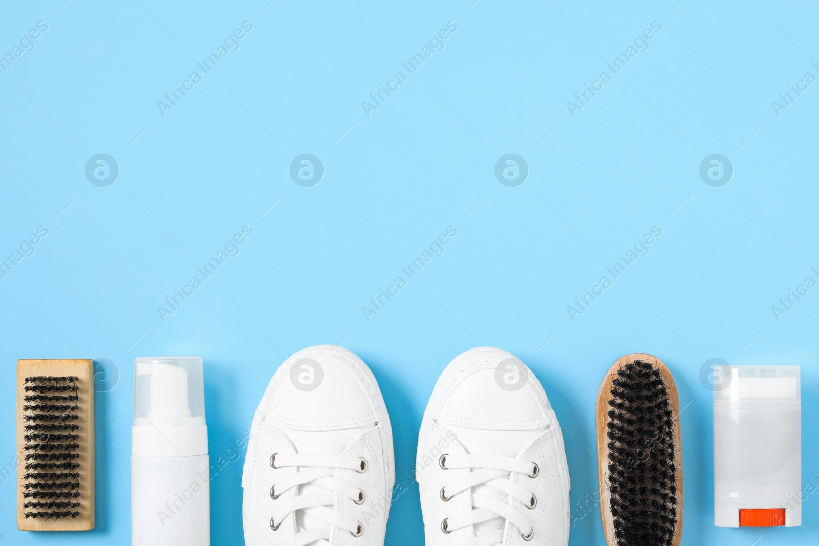 Photo of Flat lay composition with stylish footwear and shoe care accessories on light blue background, space for text