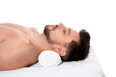 Handsome man relaxing on massage table against white background. Spa service