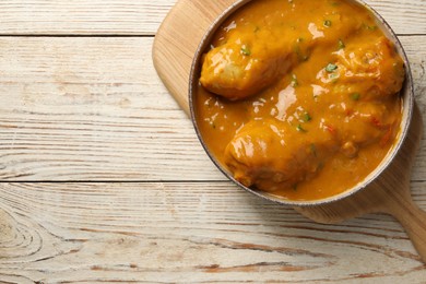 Photo of Tasty chicken curry on wooden table, top view. Space for text