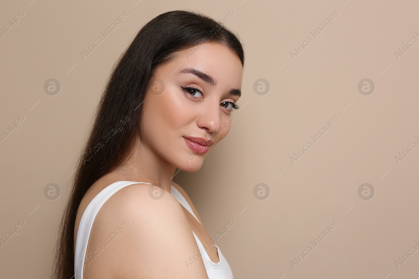 Photo of Portrait of beautiful young woman with elegant makeup on dark beige background. Space for text