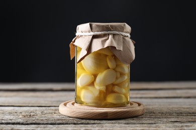 Photo of Garlic with honey in glass jar on wooden table against black background