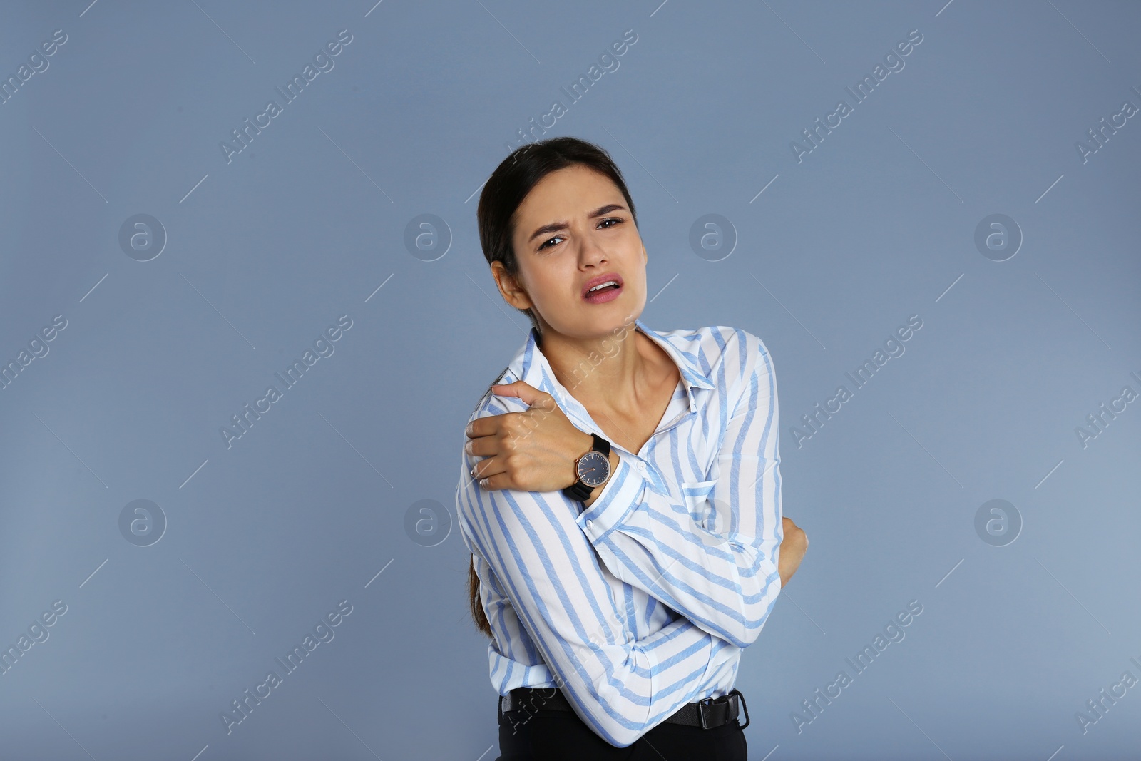 Image of Young woman suffering from shoulder pain on grey background