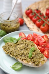 Photo of Delicious chicken breast with pesto sauce and basil on table