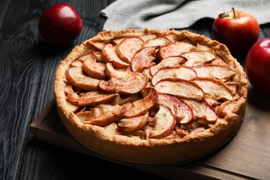 Photo of Delicious apple pie and fresh fruits on black wooden table