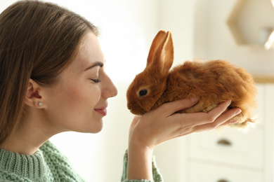 Photo of Young woman with adorable rabbit indoors, closeup. Lovely pet