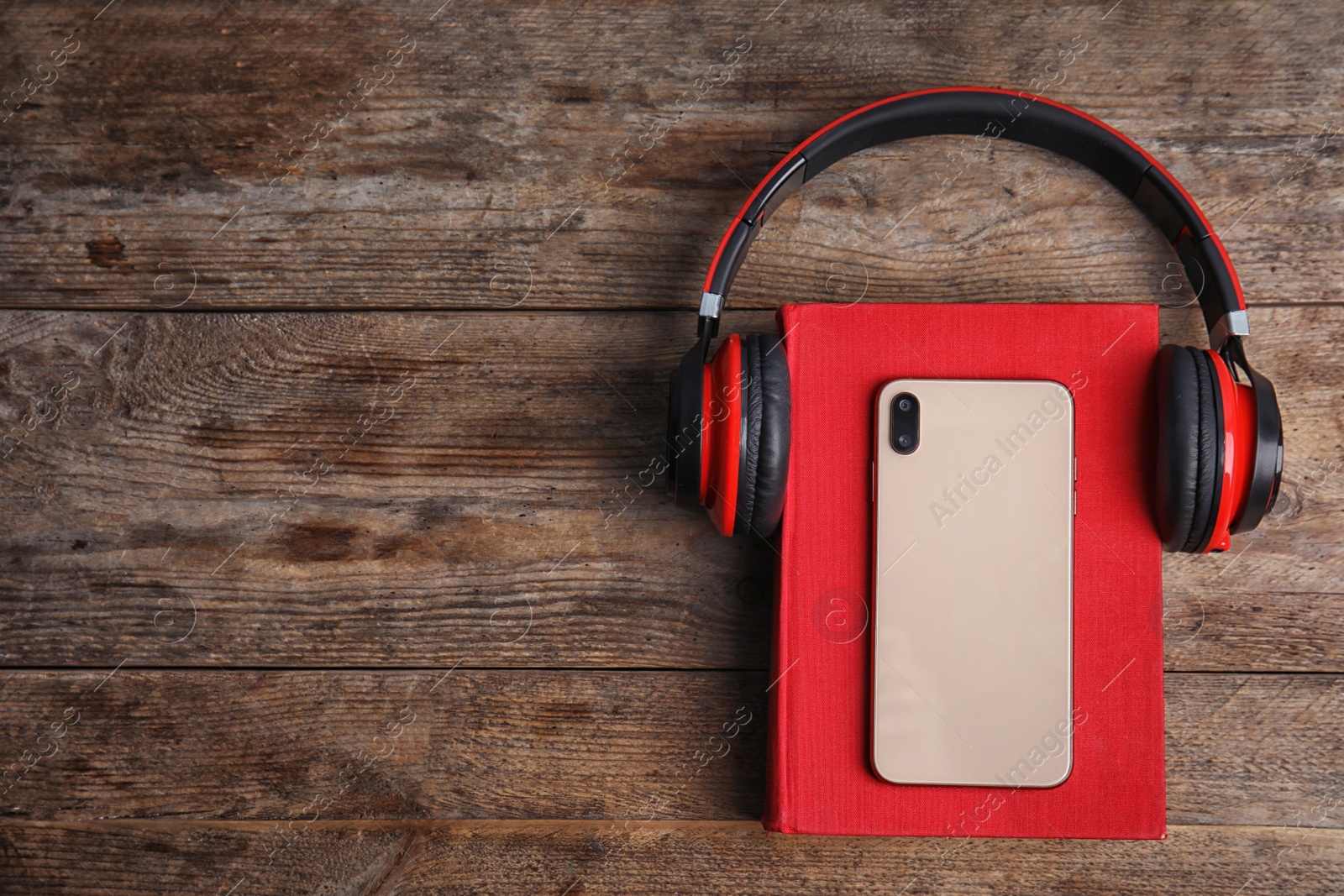 Photo of Book, modern headphones and smartphone on wooden table, top view. Space for text