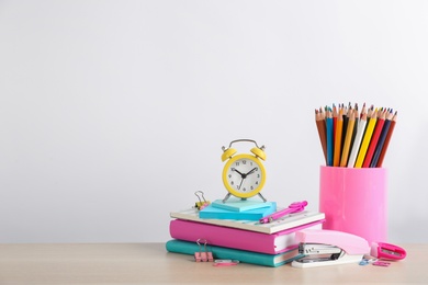 Photo of Different school stationery and alarm clock on table against white background, space for text. Back to school