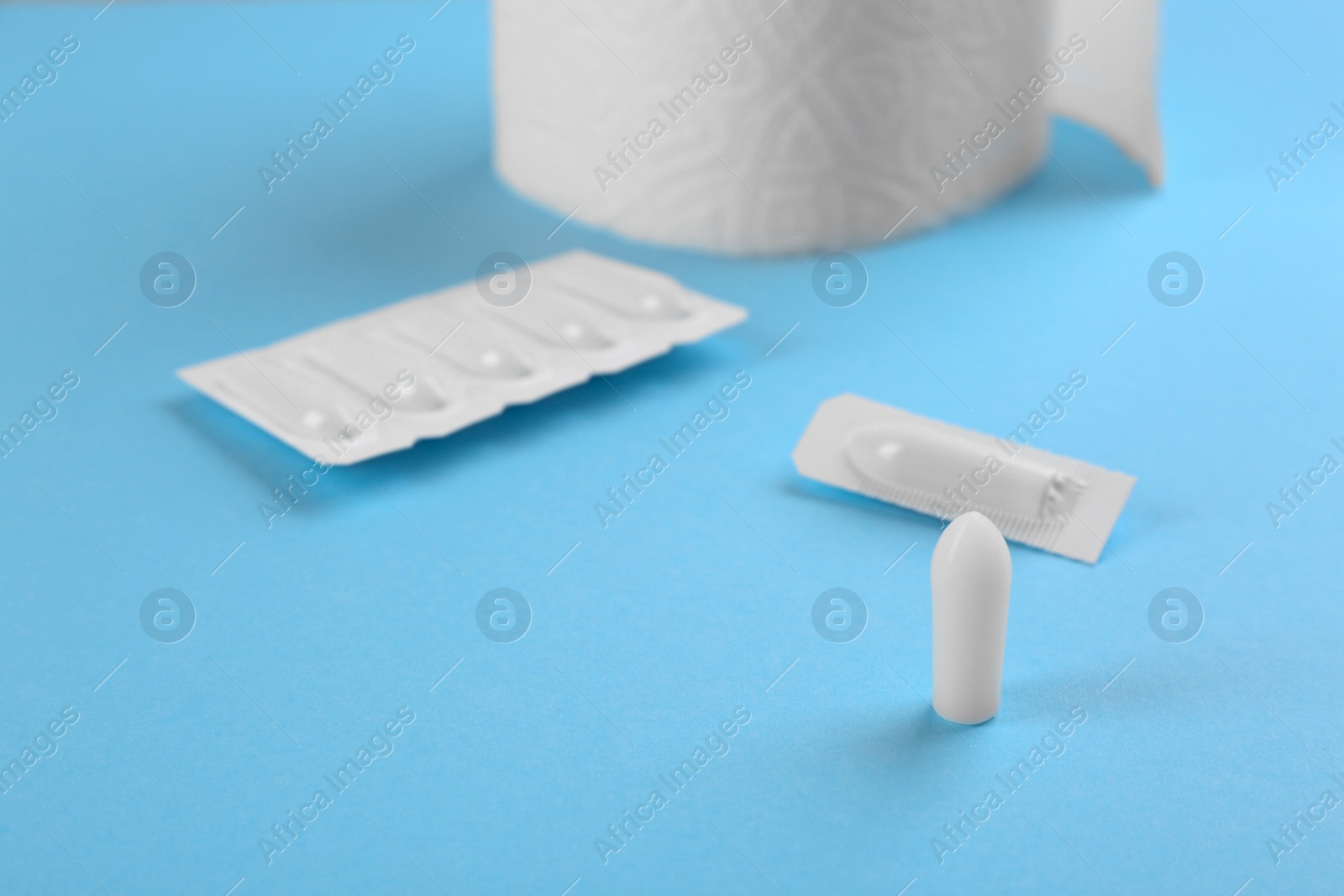 Photo of Suppositories on light blue background. Hemorrhoid treatment