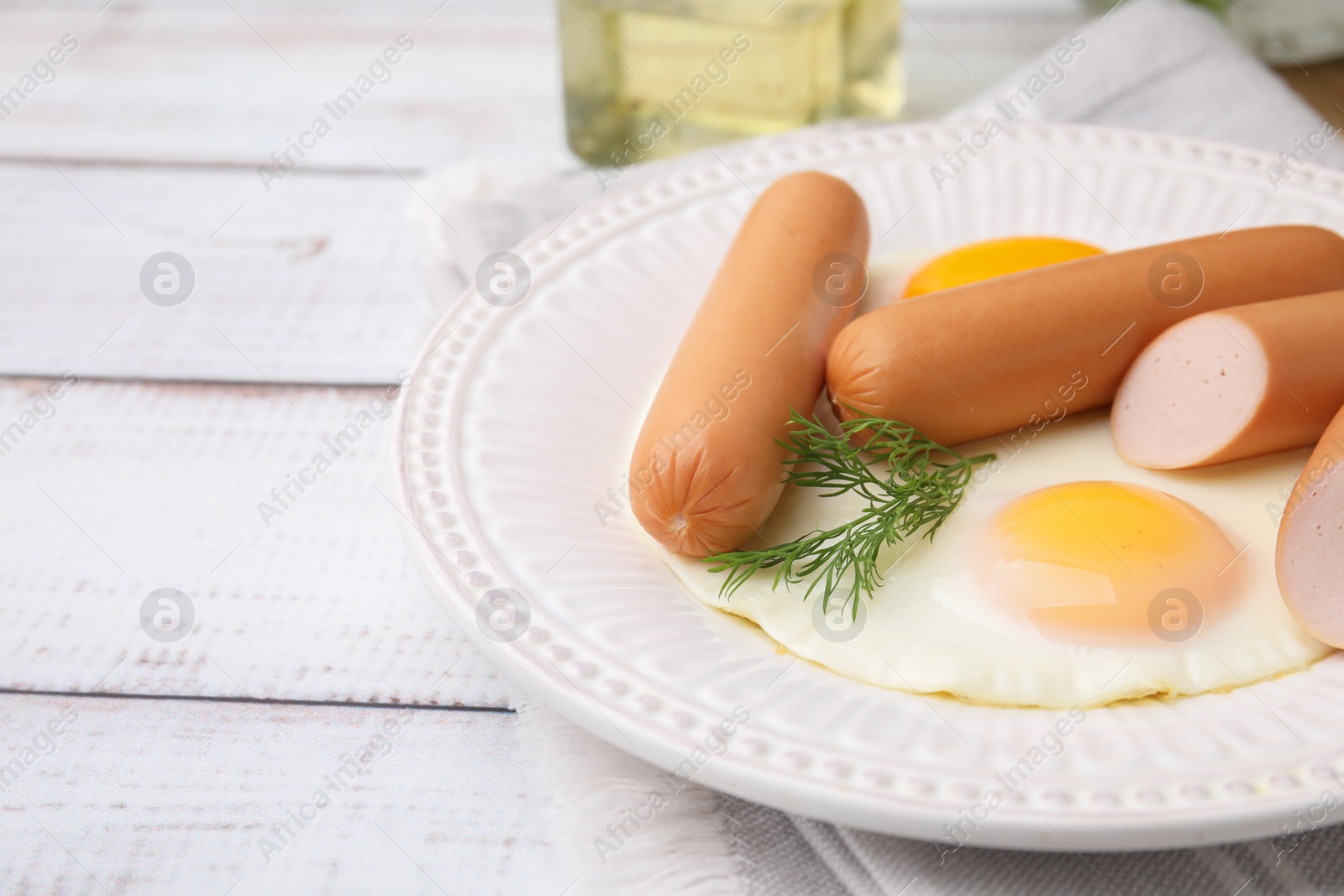 Photo of Delicious boiled sausages, fried eggs and dill on wooden table, closeup