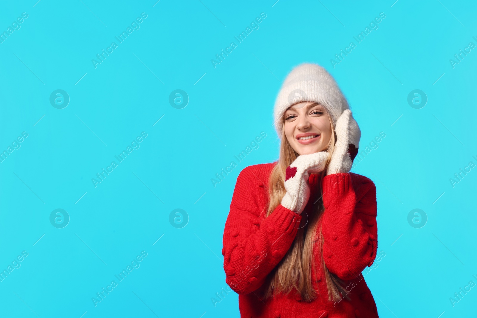 Photo of Portrait of emotional young woman in stylish hat, sweater and mittens on color background, space for text. Winter atmosphere