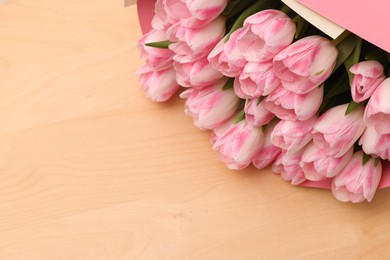 Photo of Beautiful bouquet of fresh pink tulips on wooden table, closeup. Space for text