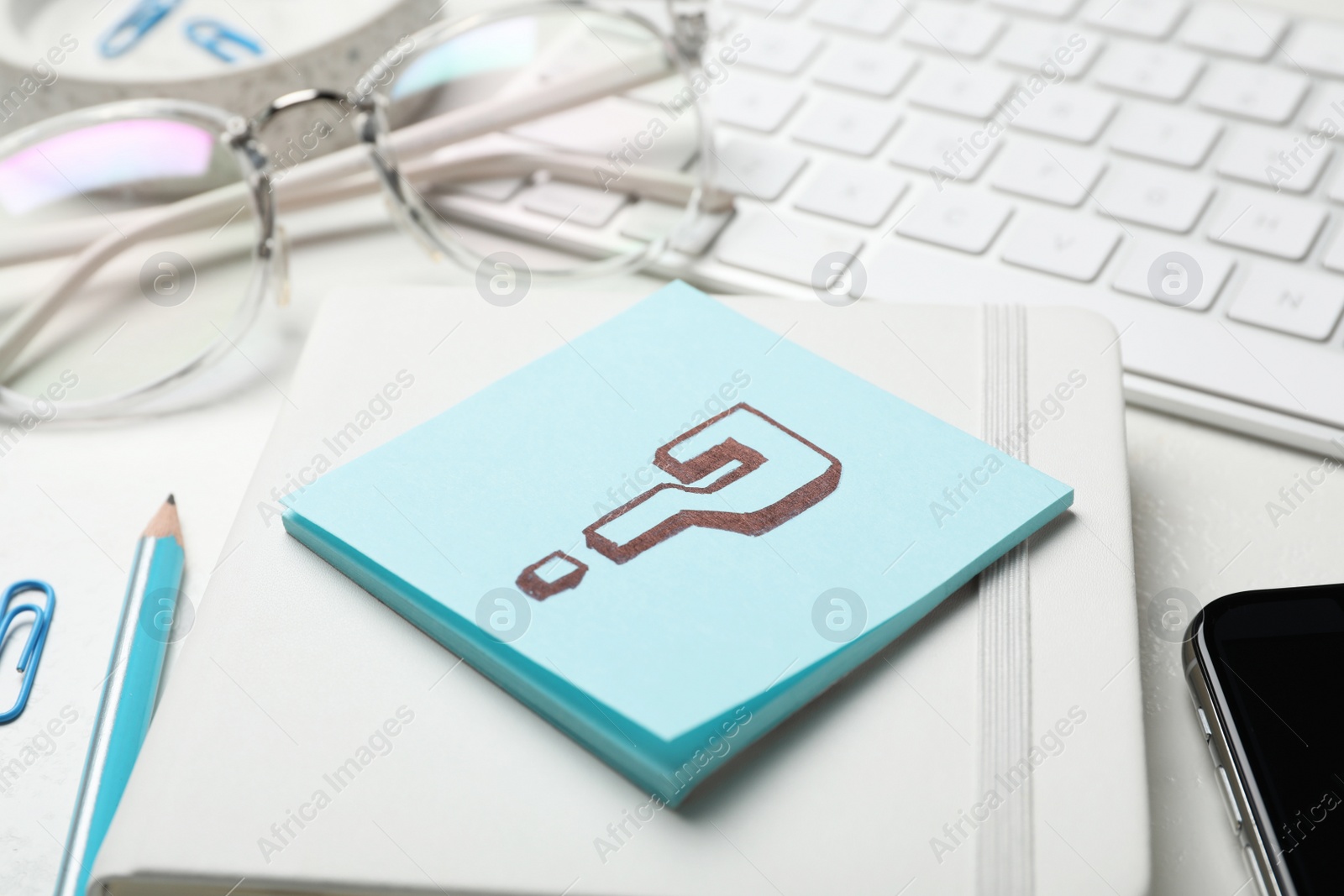 Photo of Notebook and sheet of paper with question mark on white table, closeup