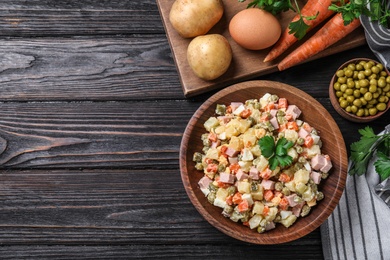 Photo of Delicious salad Olivier on black wooden table, flat lay. Space for text