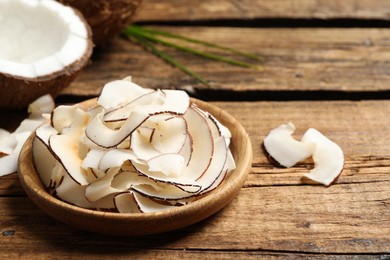Photo of Delicious coconut chips in plate on wooden table