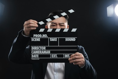Photo of Asian actor with clapperboard on stage. Film industry