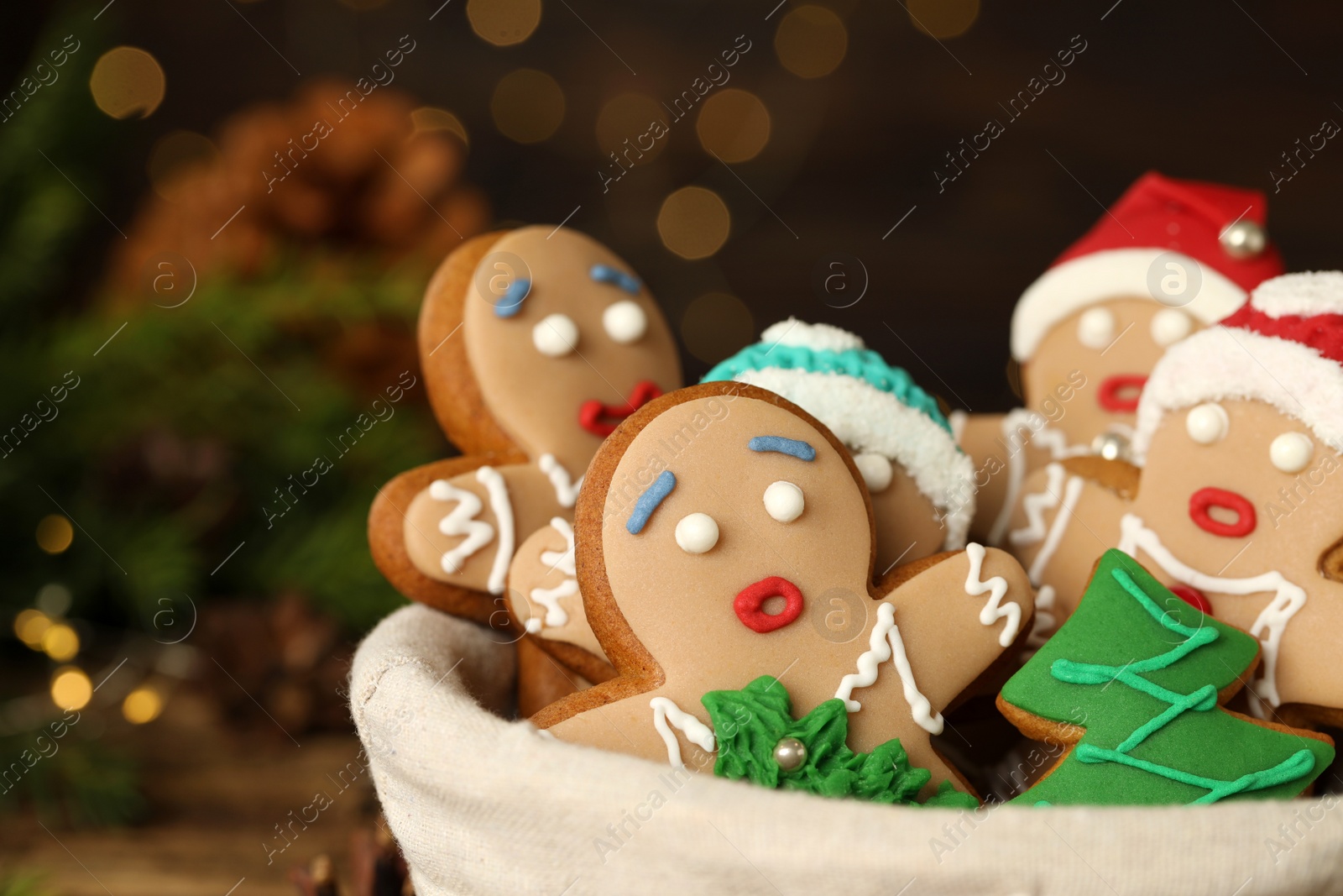 Photo of Delicious homemade Christmas cookies in bowl against blurred festive lights, closeup