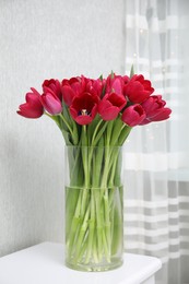 Photo of Bouquet of beautiful tulips in glass vase on white table indoors