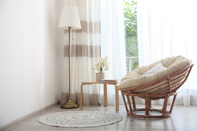 Photo of Comfortable papasan chair near window with stylish curtains in living room. Interior design