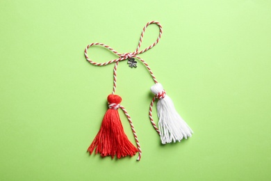 Photo of Traditional martisor on green background, top view. Beginning of spring celebration