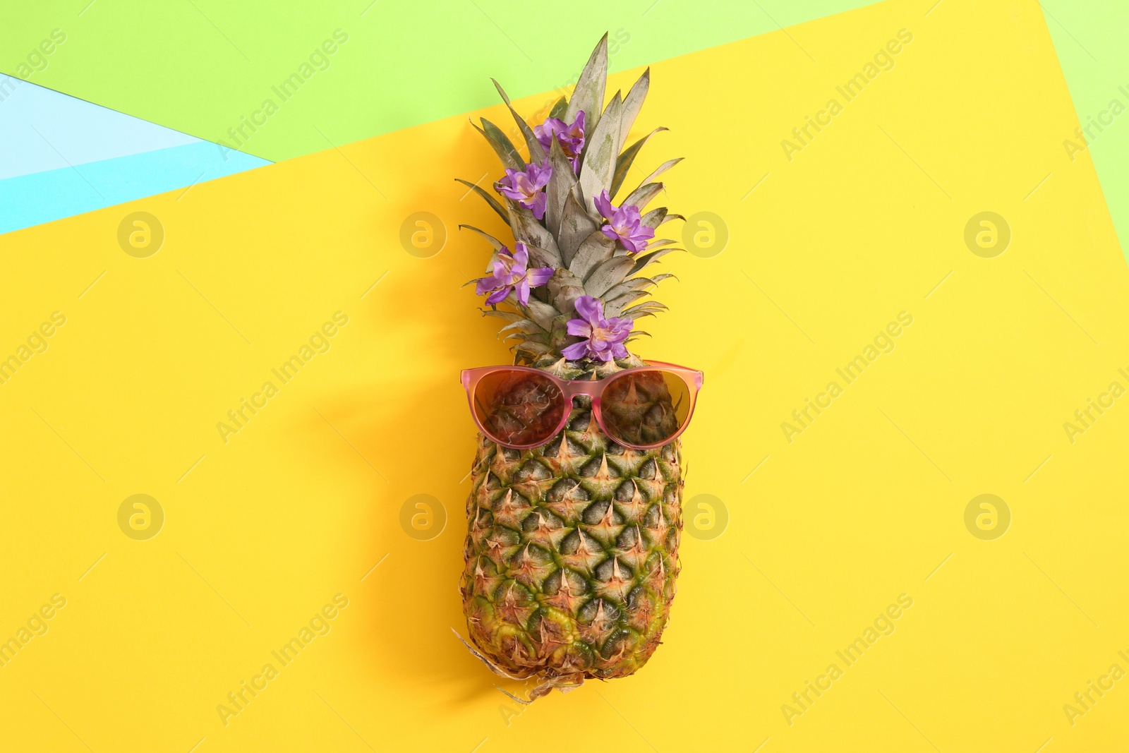 Photo of Fresh ripe pineapple with sunglasses on color background, top view