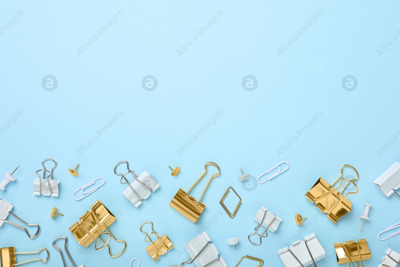 Photo of Binder clips on light blue background, flat lay. Space for text