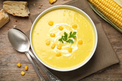 Delicious creamy corn soup served on wooden table, flat lay