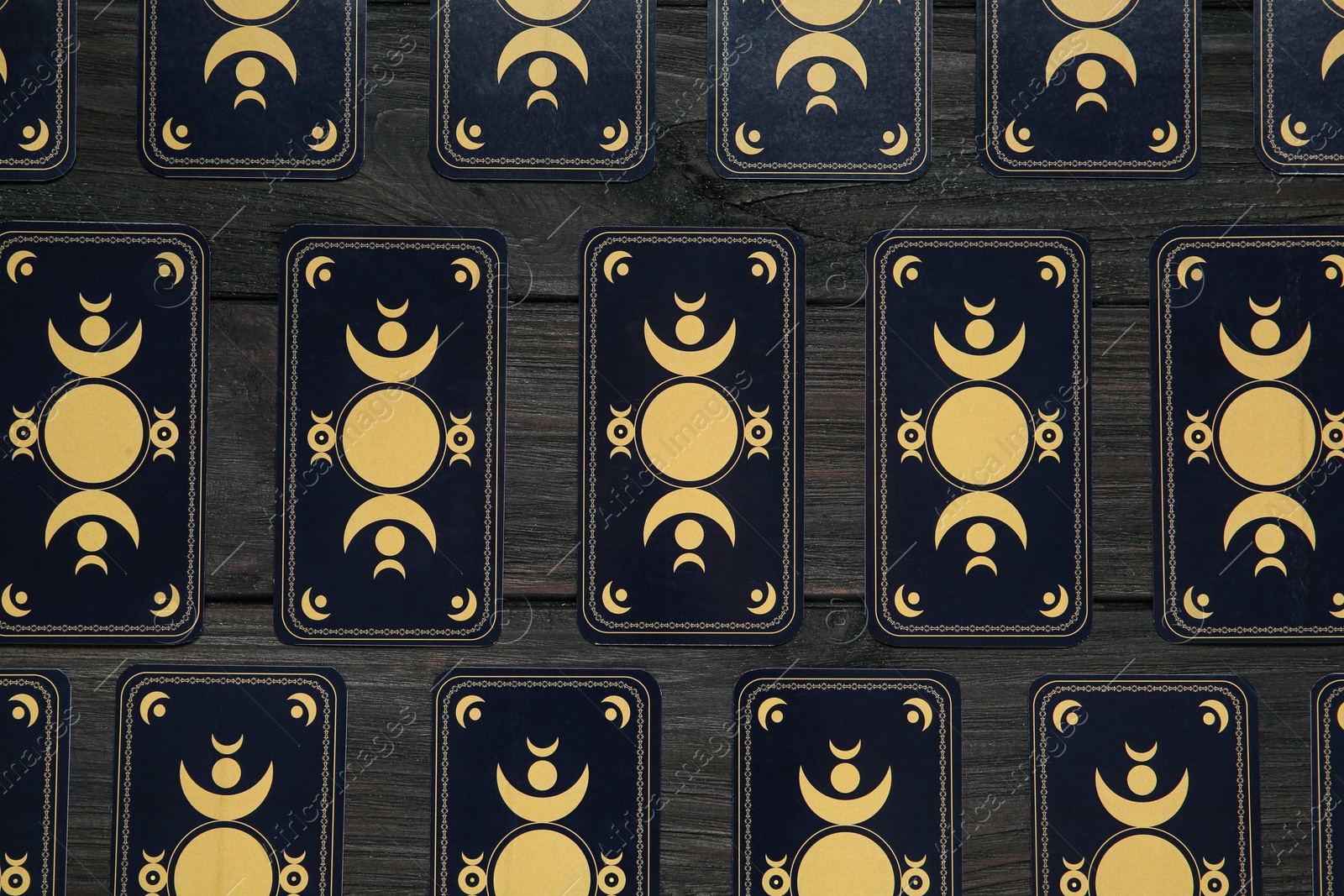 Photo of Tarot cards on black wooden table, flat lay. Reverse side