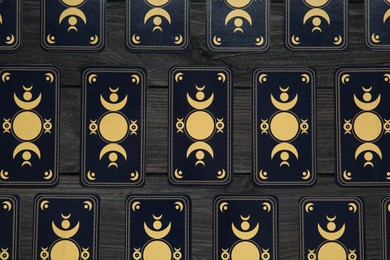 Tarot cards on black wooden table, flat lay. Reverse side